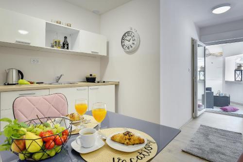 a table with two plates of food and a bowl of fruit at D&A Amphitheatre Apartments with free parking in Pula