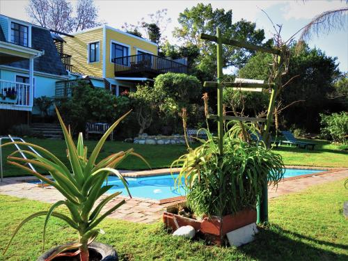 een achtertuin met een zwembad en wat planten en een huis bij Footprints of Knysna in Knysna