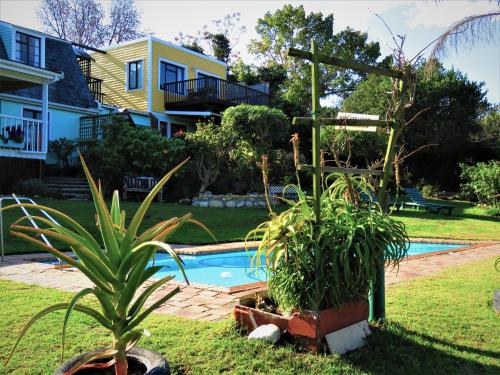 a backyard with a pool and some plants and a house at Footprints of Knysna in Knysna