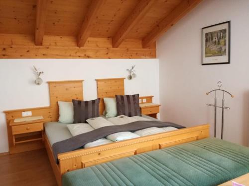 um quarto com uma grande cama de madeira e um cobertor verde em Landhaus Servus em Viehhofen