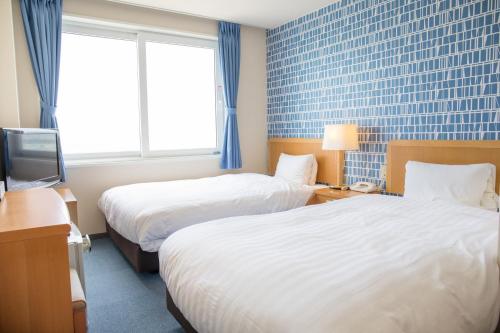 um quarto de hotel com duas camas e uma televisão em Kur and Hotel Suruga em Shizuoka
