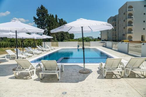 eine Gruppe von Stühlen und Sonnenschirmen neben einem Pool in der Unterkunft La Dolce Vita Residence in Ulcinj