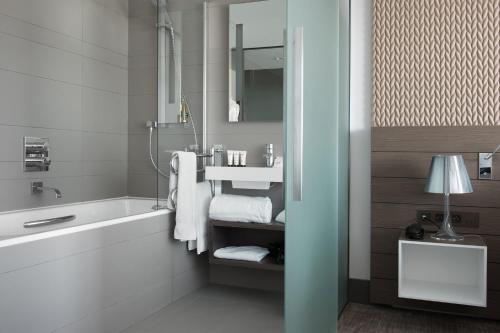 a bathroom with a tub and a sink and towels at BW Premier Collection Le Saint Antoine Hotel et Spa in Rennes