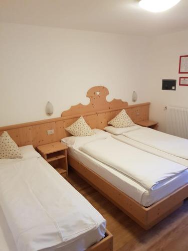 two beds in a room with white sheets at Villa Adria B&B in Canazei