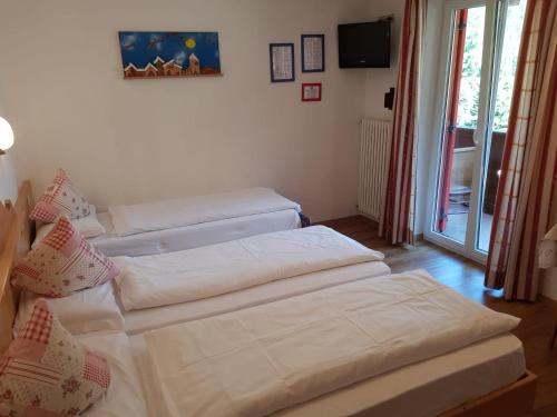 two twin beds in a room with a window at Villa Adria B&B in Canazei