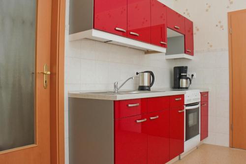a kitchen with red cabinets and a sink at Zum Dorfschullehrer in Lübbenau
