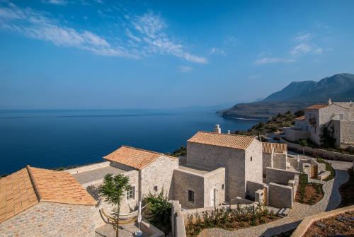 eine Luftansicht eines Hauses auf einem Hügel neben dem Wasser in der Unterkunft BASSA MAINA Villas & Suites in Areopoli