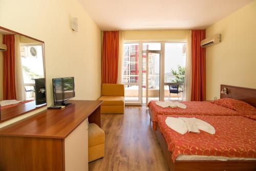a hotel room with a bed and a desk with a mirror at Iris Beach Hotel in Sveti Vlas