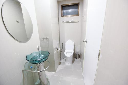 a white bathroom with a toilet and a mirror at Wish Hotel Ubon in Ubon Ratchathani