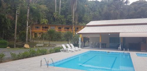 a swimming pool next to a building with a resort at Pousada Recanto do Morro in Cananéia