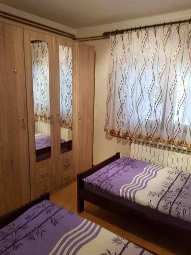 a bedroom with two beds and two windows at Apartman Anna in Ogulin