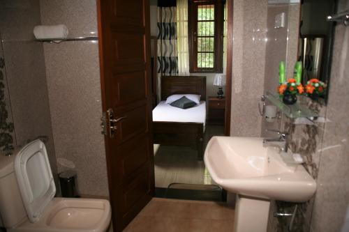 a bathroom with a toilet and a sink with a bed at The Springfields Kandy Previously Madara Residence Kandy in Kandy