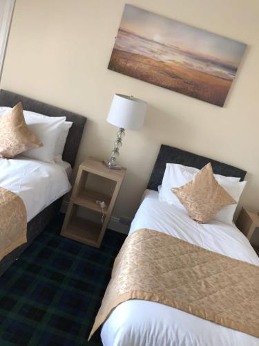 a hotel room with two beds and a lamp at Royal Guest House Nairn in Nairn