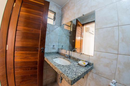 a bathroom with a sink and a wooden door at Pousada e Pensionato Dona Rosa - Crato,CE in Crato
