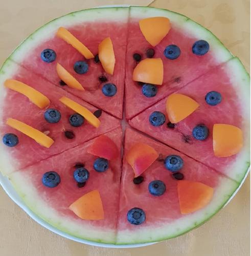 a watermelon cut into slices with blueberries and oranges at Hotel Villa Delle Palme in Cannobio