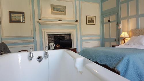 a bathroom with a bath tub next to a bed at Kelly House Country B&B in Lifton