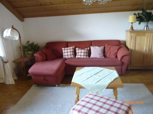 ゾントホーフェンにあるFerienwohnung Soyerのリビングルーム(赤いソファ、テーブル付)
