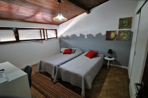 um quarto com 2 camas e almofadas vermelhas em Casa70 em Setúbal