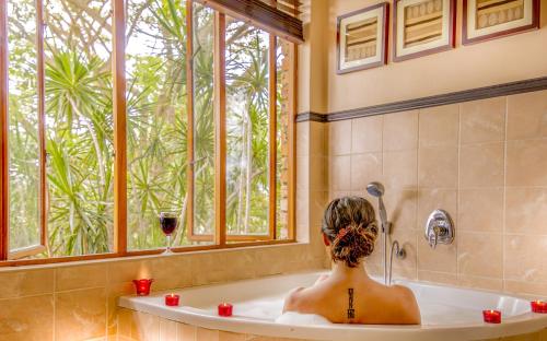a woman in a bath tub with a glass of wine at Rio Vista Lodge in Malelane