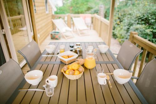 a wooden table with a basket of fruit and glasses of orange juice at Naturéo in Seignosse