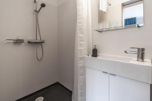 a white bathroom with a sink and a shower at Holt Inn in Flateyri