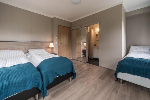 a bedroom with two beds with blue and white sheets at Holt Inn in Flateyri