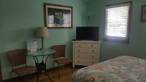 a bedroom with a bed and a table and a tv at Courtney's Place Historic Cottages & Inns in Key West