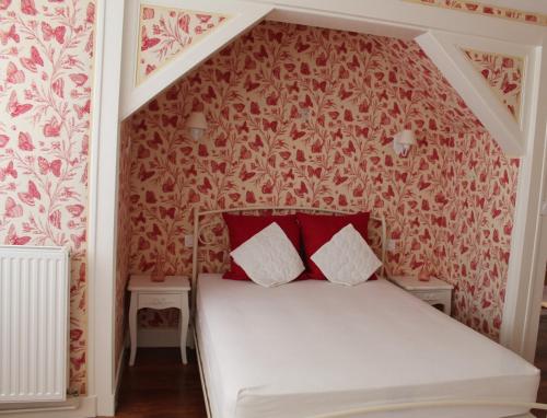 una camera da letto con un letto con carta da parati rossa e bianca di Villa d'Amoinville a Tilleau