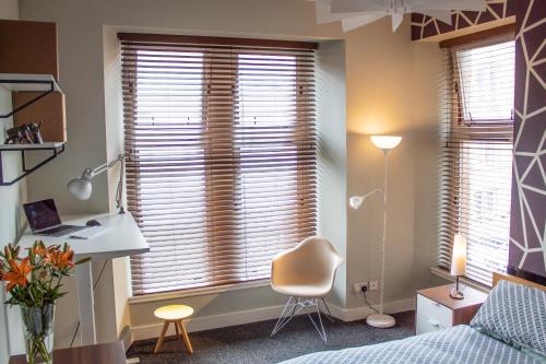 a bedroom with a bed and a desk and a window at Anchored - Unique Apartment in Glasgow's West End in Glasgow