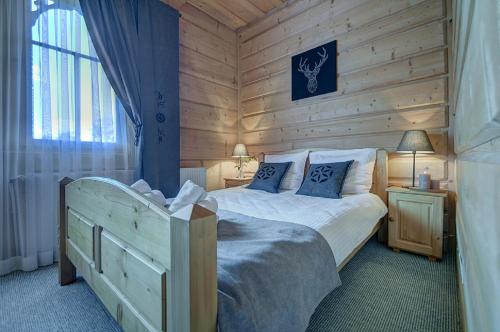 a bedroom with a bed in a wooden cabin at Willa Płazówka Białczańska in Białka Tatrzanska