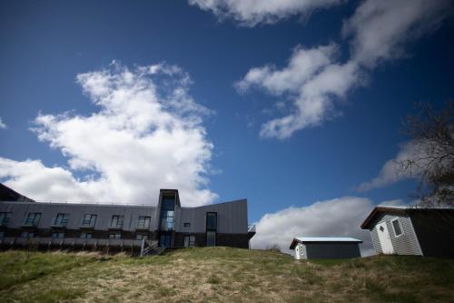 a building on top of a hill with a cloudy sky at Efri-Vík Bungalows in Kirkjubæjarklaustur