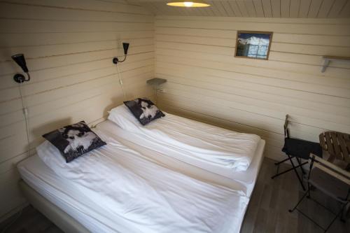 um quarto com 2 camas com lençóis brancos e almofadas em Efri-Vík Bungalows em Kirkjubæjarklaustur