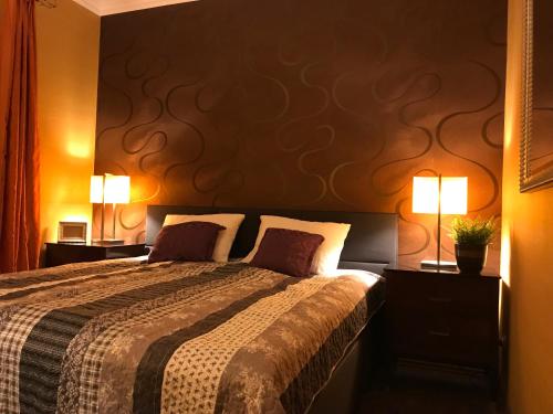 a bedroom with a large bed with two lamps at Eden Apartman in Algyő