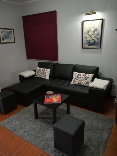 a living room with a black couch and a table at Alojamento de Santa Maria (near Siza Vieira's Church) in Marco de Canaveses