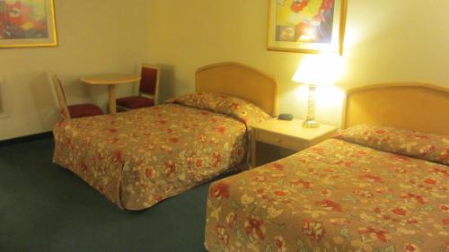 pokój hotelowy z 2 łóżkami i stołem z lampką w obiekcie El Rancho Motel Lodi w mieście Lodi