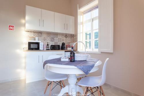 a white kitchen with a table and white chairs at Casa da Muralha in Angra do Heroísmo