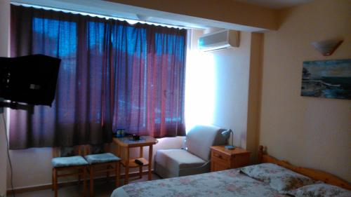 um quarto de hotel com uma cama e uma cadeira e uma janela em Hotel Tony em Nessebar