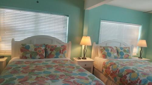2 letti in una camera da letto con pareti e finestre blu di Courtney's Place Historic Cottages & Inns a Key West