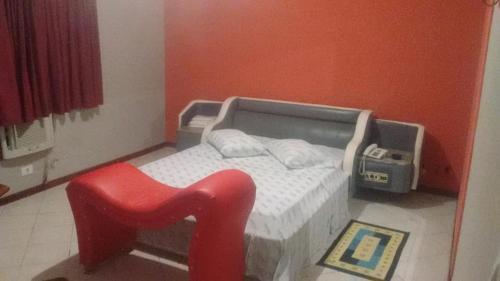 a bed with a red stool in a room at Golfinho Hotel (Adults Only) in São Vicente