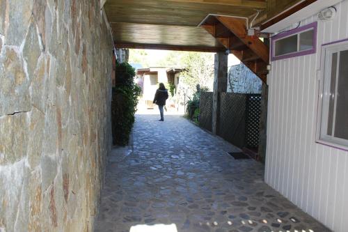 a woman walking down a stone walkway next to a building at Hostal El Conquistador in Los Vilos