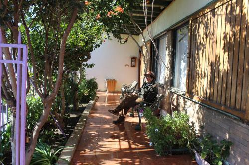 un hombre sentado en un banco junto a un edificio en Hostal El Conquistador, en Los Vilos