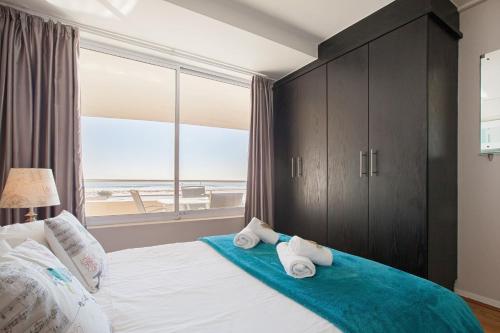 a bedroom with a bed with a view of the ocean at Lagoon Beach 136 by CTHA in Cape Town