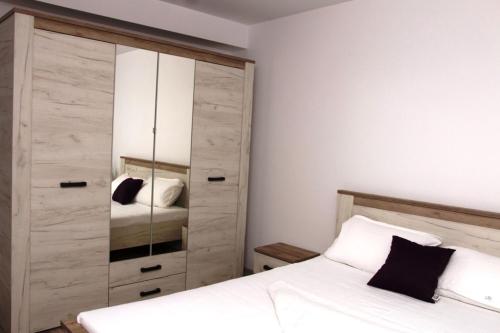 a bedroom with a bed and a large cabinet at Apartament Serenity Mamaia Nord in Mamaia Sat/Năvodari