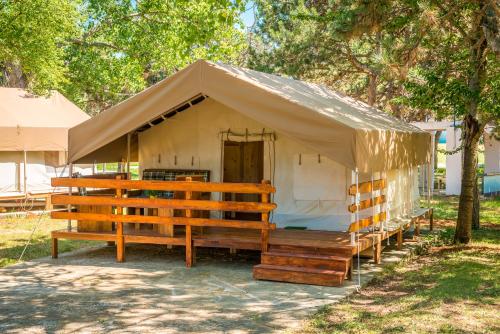 a large tent with wooden benches in a field at SunFlower Camping Savudrija in Savudrija