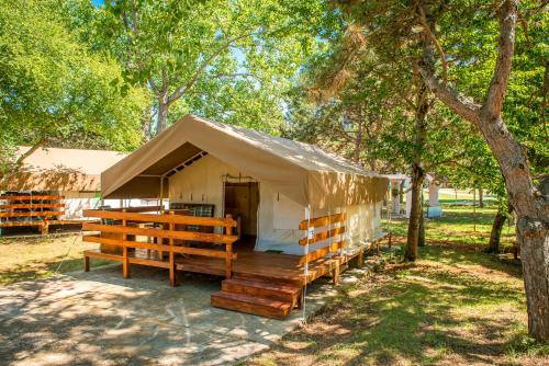 a tent with wooden benches in a park at SunFlower Camping Savudrija in Savudrija