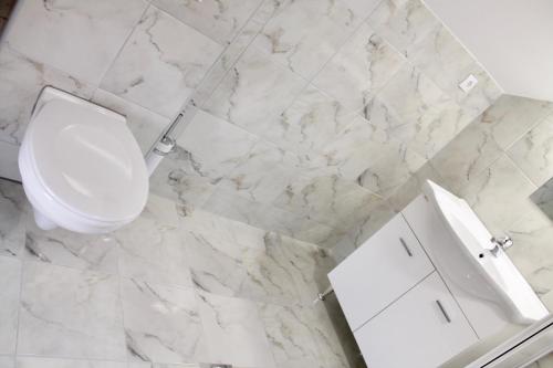 uma casa de banho branca com WC e paredes em mármore em Apartments Villa Milna 1 em Budva