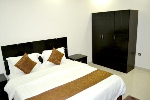 a bedroom with a large white bed with brown pillows at الخربوش للشقق المخدومة in Hafr Al Baten