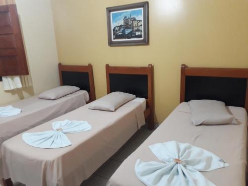 una camera con due letti con lenzuola bianche di Pousada Rural Veredas a Três Marias