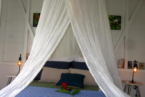Schlafzimmer mit Himmelbett und weißen Vorhängen in der Unterkunft Or bleu-Bungalow volcan Soufriere-Vue sur mer in Saint-Claude