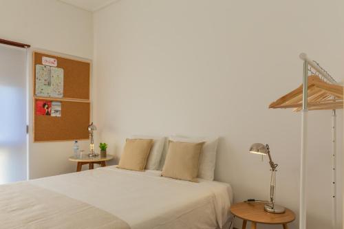 リスボンにあるAlface Roomのベッドルーム1室(白いベッド1台、テーブル2台付)